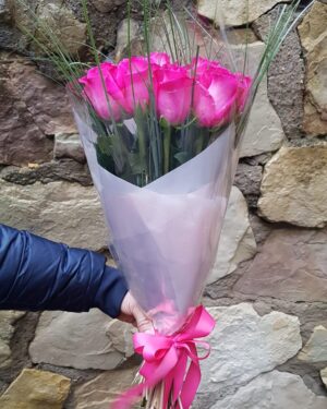 Rozā rožu pušķis dekoratīvā iepakojumā